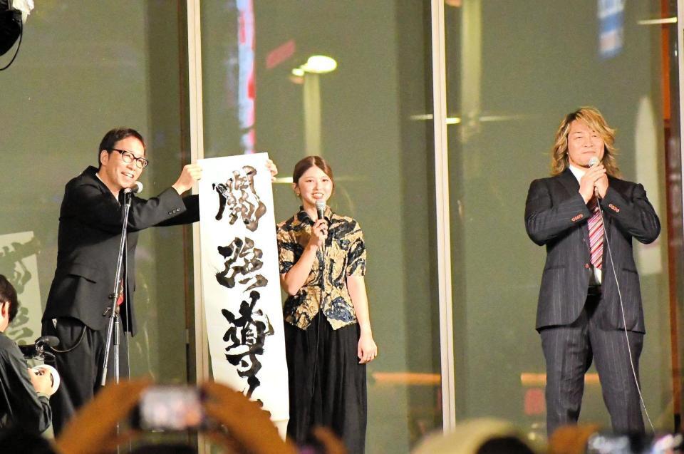 　歌舞伎町で行われた１・４東京ドーム大会の公開記者会見で「闘強導夢」と書をしたためたゲストの竹内朱莉（中央）。右は棚橋弘至