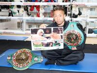 　試合写真を手にポーズを決める井上拓真（撮影・石井剣太郎）