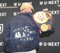 　ジャケットの背中の文字を披露する堤聖也（撮影・金田祐二）