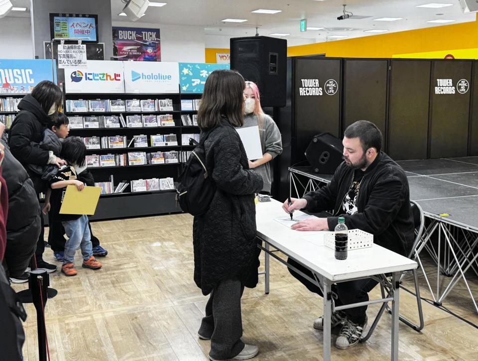 集まったファン１人１人と会話しながらサインをするウルフアロン（右端）