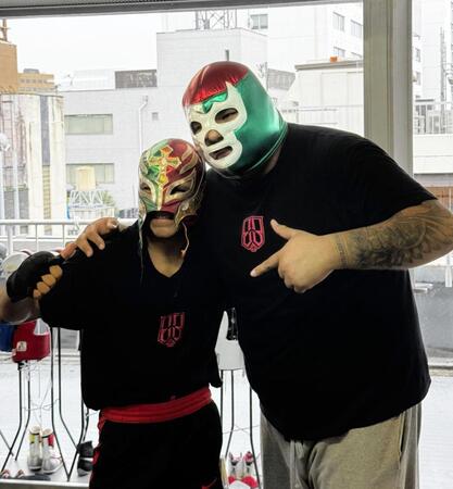 レイ・ミステリオのマスクをかぶってポーズを取るエリック・バディージョ（左）と実弟のイバン・バディージョトレーナー