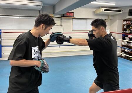 武市晃輔トレーナー（左）の構えるミットへ左ストレートを打ち込む西田凌佑＝六島ジム