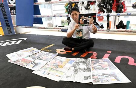 那須川天心戦を報じる各スポーツ新聞を前に試合の写真を手にする井上拓真（撮影・堀内翔）