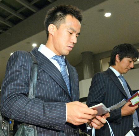 パスポートを手に飛行機へ乗り込む岡崎