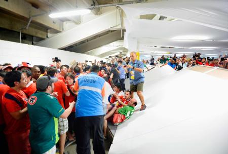 　試合開始前にマラカナン競技場に乱入したチリサポーター。右は壊された壁＝リオデジャネイロ（共同）