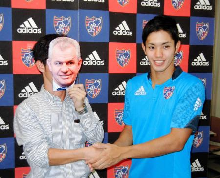 　日本代表アギーレ監督のお面を手にした関係者との２ショットに笑顔を見せる、ＦＣ東京のＦＷ武藤（右）