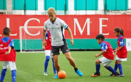 　タイの首都バンコク郊外で開かれたサッカー教室で、小学生と対戦する本田圭佑選手＝２７日（共同）