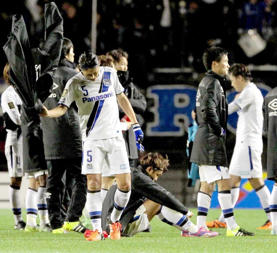 　ピッチに座りうなだれるＧ大阪・宇佐美（中央）と、グラウンドコートをたたきつける丹羽（左）