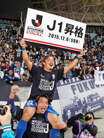 　同点ゴールの福岡・中村北斗はＪ１昇格のボードを手に笑顔をみせる