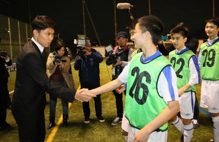　フィテッセへの移籍記者会見後、ＦＣ東京Ｕ－１５深川の選手たちに握手で見送られる太田（左）＝ＦＣ東京深川グラウンド
