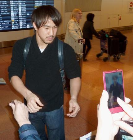　帰国し、ファンにサインをするサッカー日本代表の岡崎慎司＝２１日午前、羽田空港