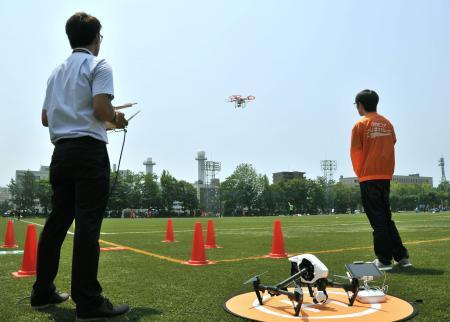 　サッカーの試合を小型無人機「ドローン」で撮影する関係者＝２８日、秋田市