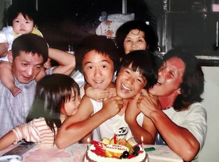 小学時代、誕生日ケーキを前に笑顔の山口蛍（右から２人目）右端は父憲一さん、右から３人目は兄岬さん（父憲一さん提供）