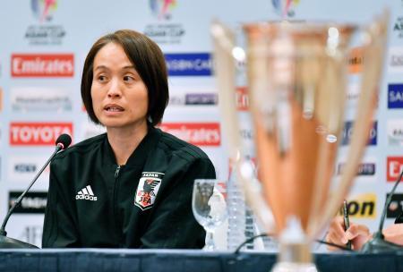 　オーストラリアとの決勝戦を前に記者会見するサッカー女子日本代表の高倉監督。右は優勝杯＝１９日、アンマン（共同）