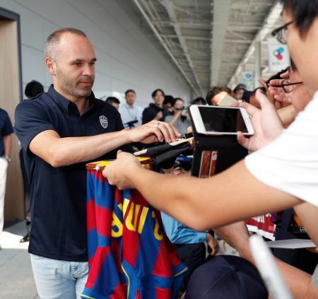 　関西空港に到着し、ファンのサインの求めに応じるＪ１神戸のアンドレス・イニエスタ選手（左）＝１８日午前