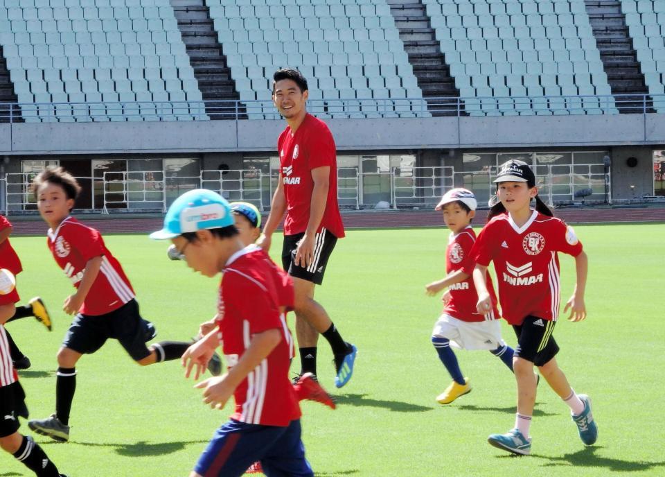 子供たちとサッカーをして笑顔を見せる香川真司
