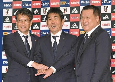 　田嶋会長（右）、関塚技術委員長（左）と手を合わせ笑顔を見せる