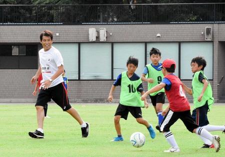 　子供たちとサッカーをする西野朗氏（左）