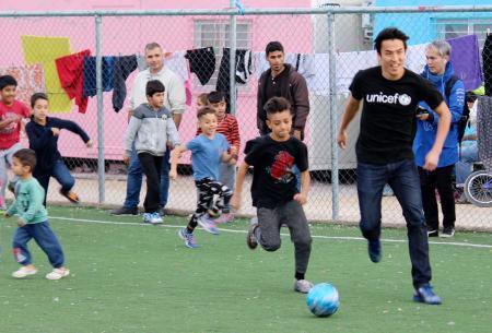 　アテネの難民キャンプで、子供たちとボールを追う長谷部誠選手（右端）＝１２日（共同）