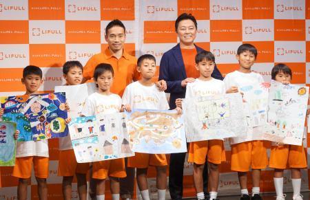 　東京都内で開かれたイベントで、子どもたちと記念撮影に応じるサッカー日本代表の長友（奥左）＝１２日