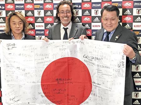 　サポーターや関係者のメッセージ入り日の丸を受け取ったラモス監督（中央）。左は北沢理事、右は田嶋会長