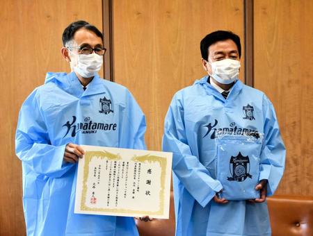 大西秀人高松市長（右）に寄贈品のポンチョを手渡したＪ３讃岐・池内秀樹社長