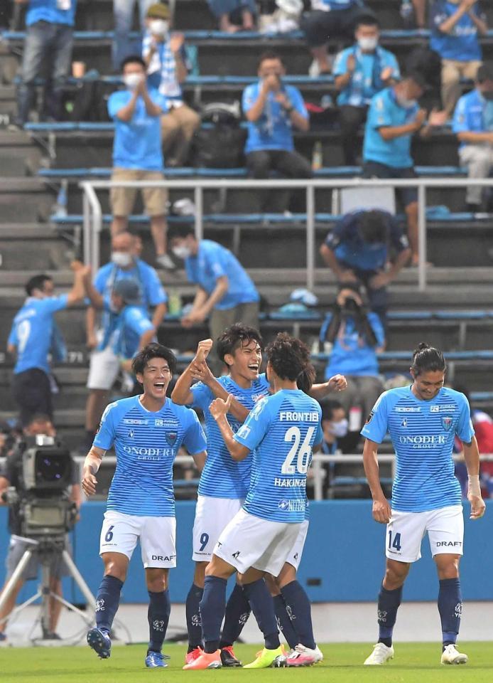 　前半、先制ゴールを決め、イレブンとサポーターに祝福される横浜ＦＣ・一美（中央左）