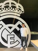 　エンブレムの前に立つ中井卓大（提供写真）