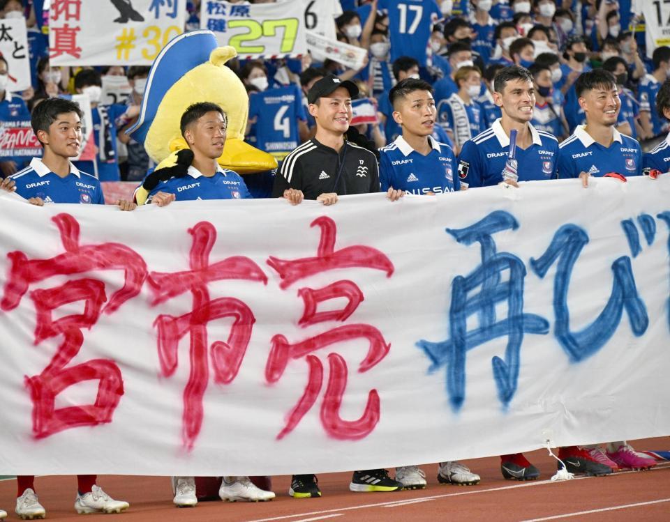 　試合後、宮市（左から３人目）を迎えて応援メッセージが書かれた横断幕を掲げる横浜Ｍイレブン
