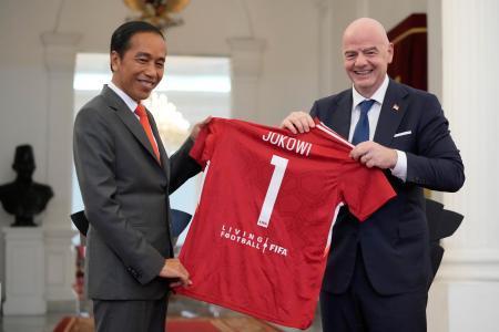　１８日、インドネシア・ジャカルタで、ＦＩＦＡのインファンティノ会長（右）から記念のジャージーを受け取るジョコ大統領（ＡＰ＝共同）
