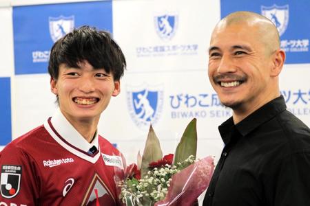 　近藤岳登氏（右）に花束で祝福される泉柊椰（びわこ成蹊スポーツ大学提供）