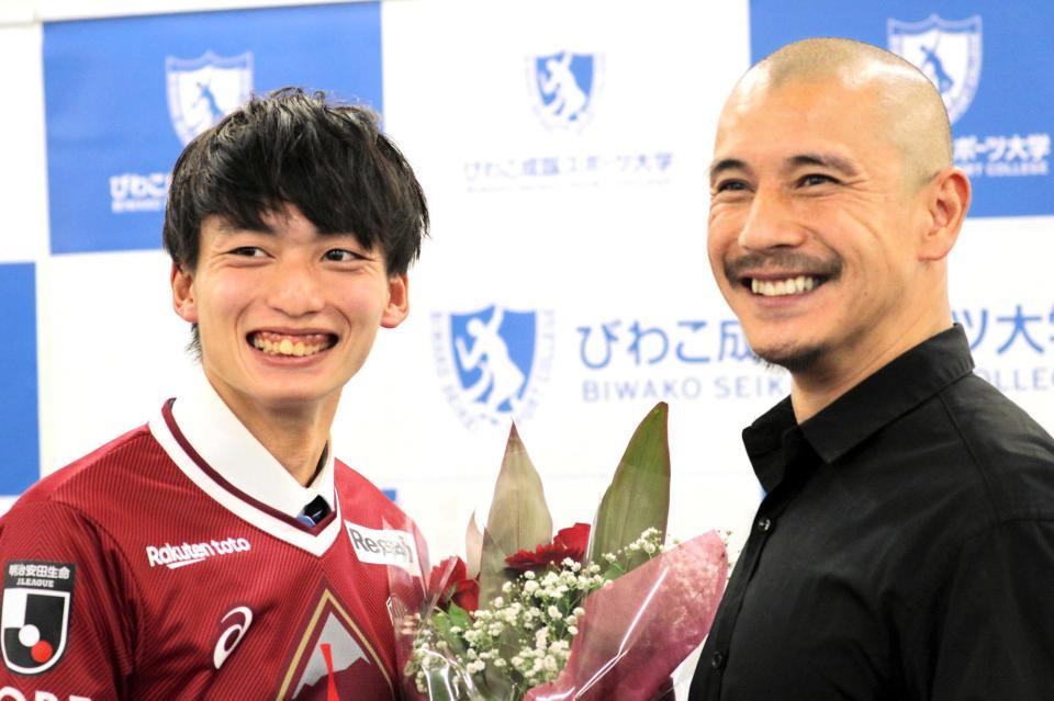 　近藤岳登氏（右）に花束で祝福される泉柊椰（びわこ成蹊スポーツ大学提供）
