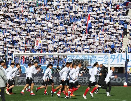 　皆でボードを掲げて横浜Ｍイレブン（手前）を鼓舞する横浜Ｍサポーター（撮影・吉澤敬太）