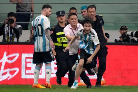 　中国北京市で１５日に開かれたサッカーの国際親善試合で、ピッチ上を走るファン（手前）を見るアルゼンチン代表のメッシ選手（ＡＰ＝共同）