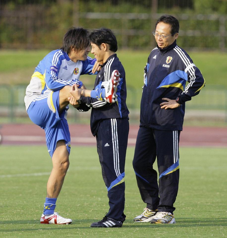 　ストレッチで体をほぐす遠藤保仁と話をする岡田監督（右端）＝２００９年