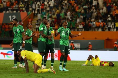 　アフリカ選手権準々決勝を終え、勝利を喜ぶナイジェリアの選手たちと倒れ込むアンゴラの選手たち＝２日、アビジャン（ロイター＝共同）