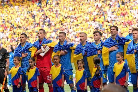 　ルーマニア戦のキックオフ前に、国旗をまとって国歌を斉唱するウクライナのイレブン＝ミュンヘン（ＡＰ＝共同）