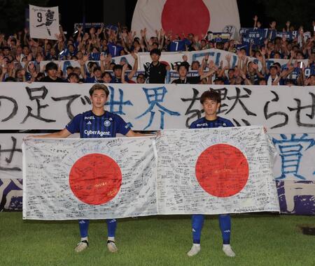 　藤尾（左）とともに日の丸を持つ町田・平河（撮影・西岡正）