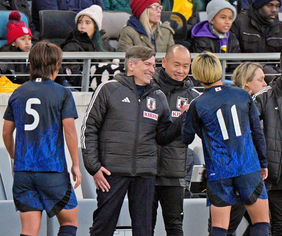 　後半、交代した田中（１１）を笑顔で迎えるニールセン監督（左から２人目）＝共同