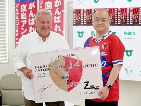 　茨城県鹿嶋市役所で、田口伸一市長（右）に記念パネルを贈るジーコさん＝９日