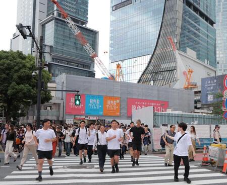 　東京・渋谷のスクランブル交差点を走る本田圭佑。奥はＪＲ渋谷駅（撮影・吉澤敬太）