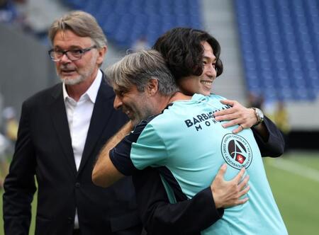 　モナコの関係者とハグを交わす南野拓実。左奥はフィリップ・トルシエ氏（撮影・中田匡峻）