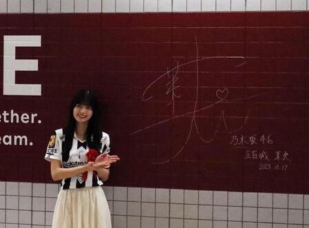 　駅の壁面にサインする五百城茉央（撮影・中野裕美子）