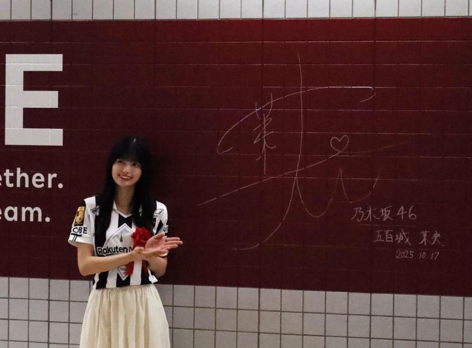 　駅の壁面にサインする五百城茉央（撮影・中野裕美子）