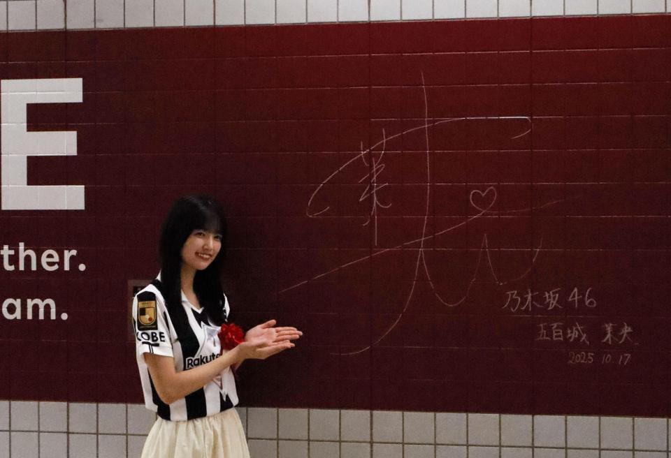 　駅の壁面にサインする五百城茉央（撮影・中野裕美子）