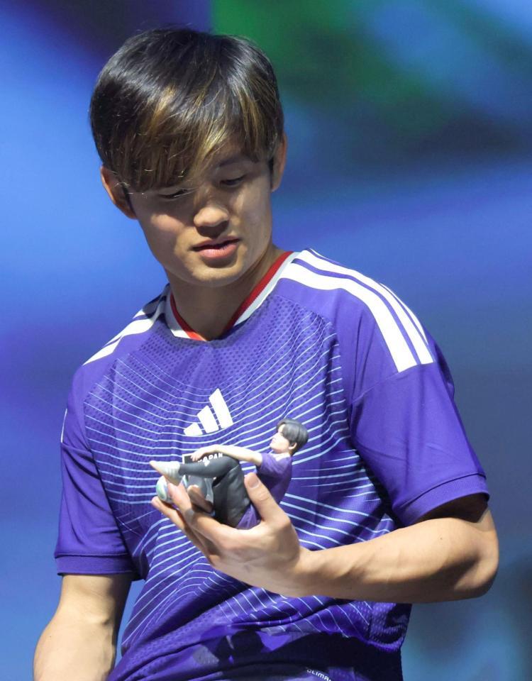 　プレゼントされた人形に見入るサッカー日本代表・久保建英（撮影・西岡正）