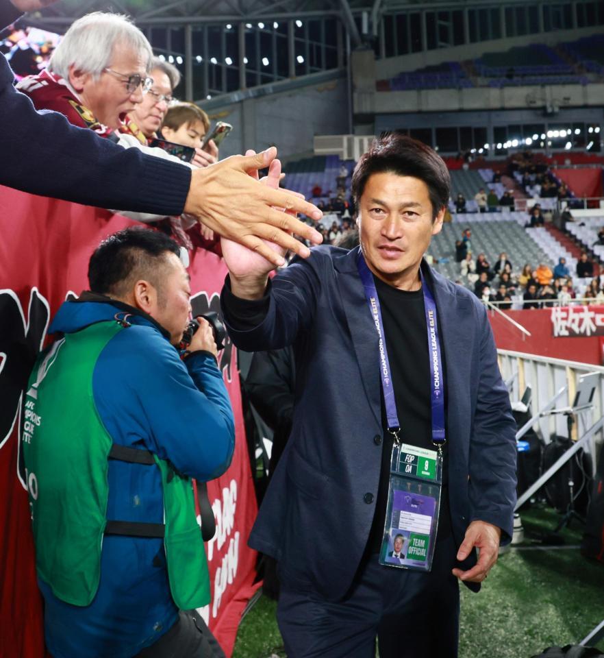 　サポーターとタッチを交わす神戸・吉田孝行監督（撮影・立川洋一郎）