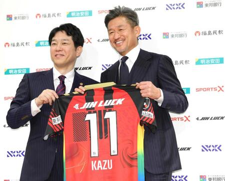 　小山淳代表取締役ＣＥＯ（左）と共に背番号１１のユニホームを持つ福島・三浦知良