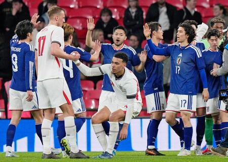 　サッカー国際親善試合でイングランドから初勝利を挙げ、タッチを交わす菅原由勢（奥中央）ら日本代表＝３月３１日、ロンドンのウェンブリー競技場（共同）
