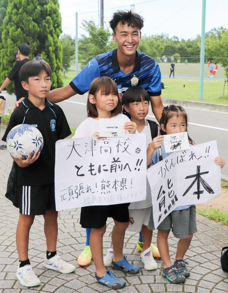 　「がんばれ！熊本」と書かれた紙を持つ子どもらと写真に納まる、大津高の西本瑛司（奥）